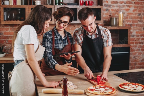 Woman teaching her friends how to cook. Group of people cutting