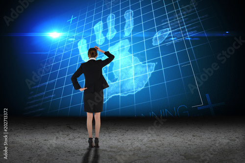 Young businesswoman standing and thinking against hand print on blue grid