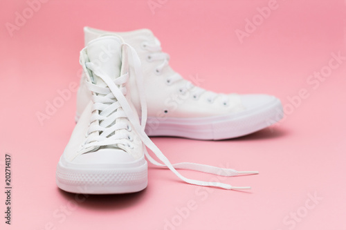 Pair of new white sneakers on pink background