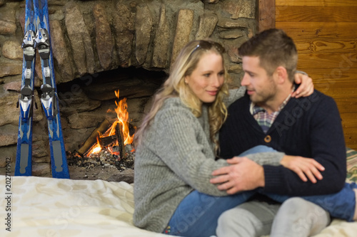 Romantic couple with arms around in front of lit fireplace