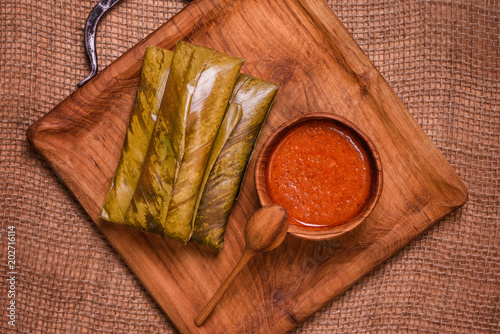 top view of sticky rice wrapped in leaves and served with peanut sauce on wooden plate. Famous cuisine in Borneo. Brunei, Sarawak and Sabah. Called Kelupis. photo