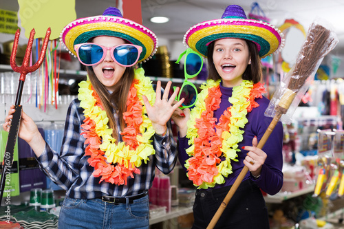Two cheerful young female friends having fun in festival outfits store