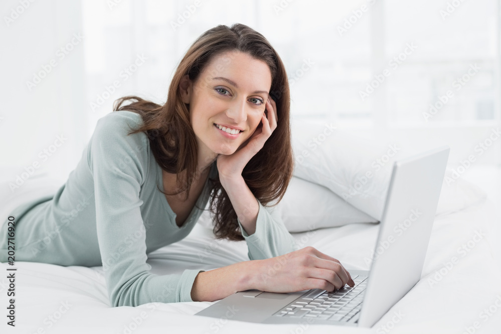 Relaxed casual smiling woman using laptop in bed Relaxed casual smiling woman using laptop in bed