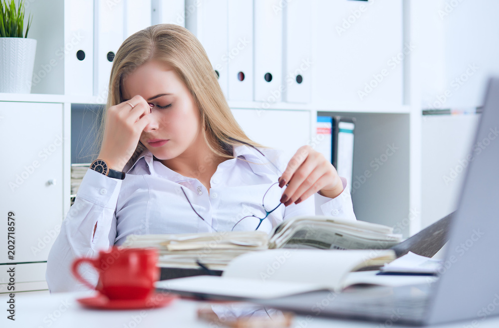 Tired Caucasian businesswoman holding eyeglasses and massaging nose bridge. Girl feeling discomfort from long wearing glasses at workplace. Tired Caucasian businesswoman holding eyeglasses and massaging nose bridge. Girl feeling discomfort from long wearing glasses at workplace.