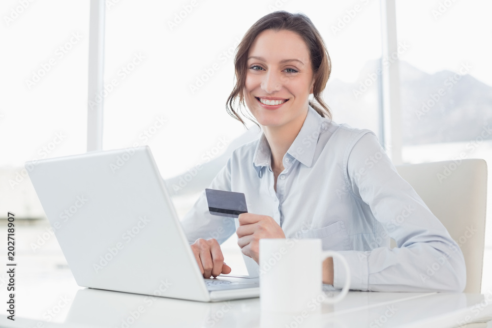 Smiling businesswoman doing online shopping in office Smiling businesswoman doing online shopping in office