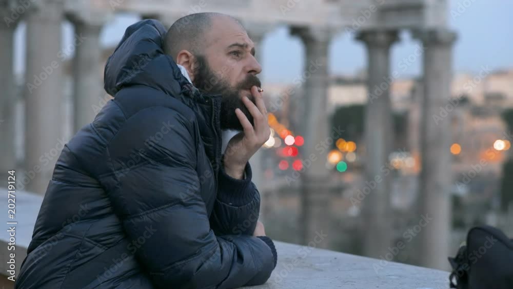 Thoufgtful sad handsome man smoking cigarette- Rome in background Thoufgtful sad handsome man smoking cigarette- Rome in background