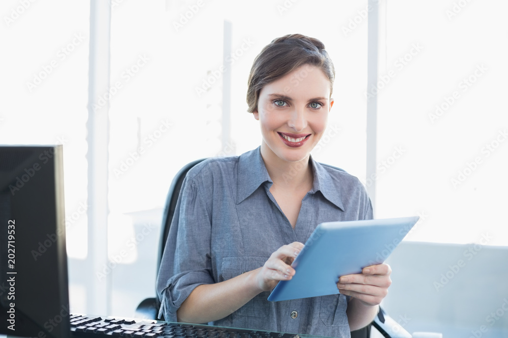 Portrait of attractive young businesswoman using her tablet sitting at her desk