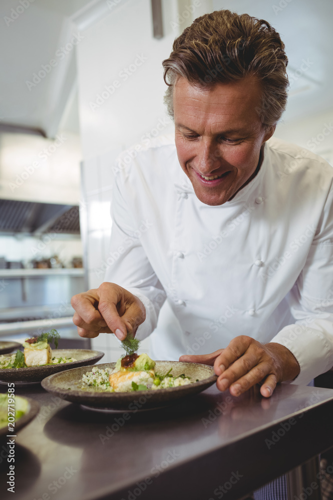 Male chef examining appetizer plates at order station Male chef examining appetizer plates at order station