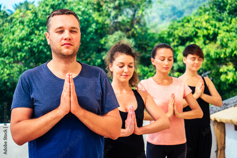 a group of people practicing yoga in the group making the gesture of namaste