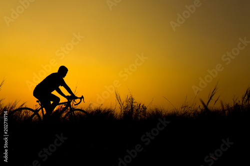 Silhouette of cyclist with friend in motion on the background of beautiful sunset