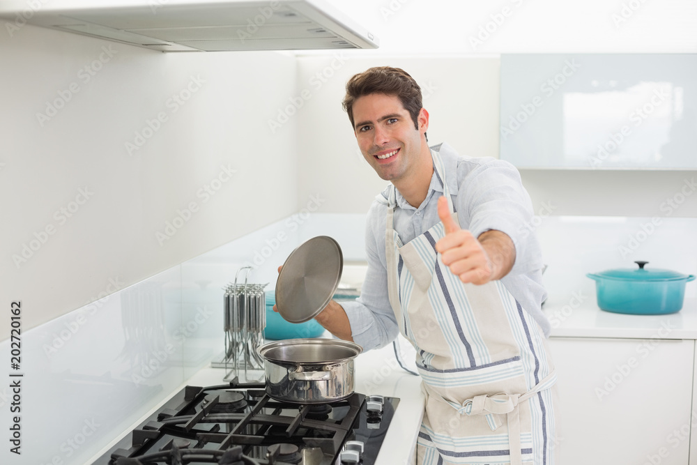 Smiling young man gesturing thumbs up in kitchen Smiling young man gesturing thumbs up in kitchen