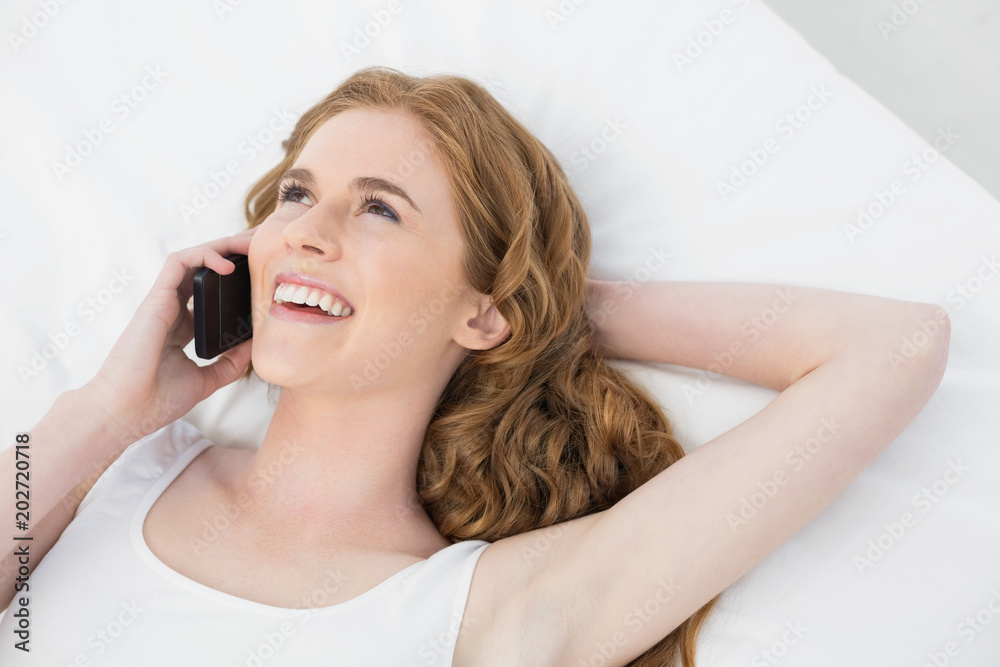 Cheerful woman using mobile phone in bed Cheerful woman using mobile phone in bed