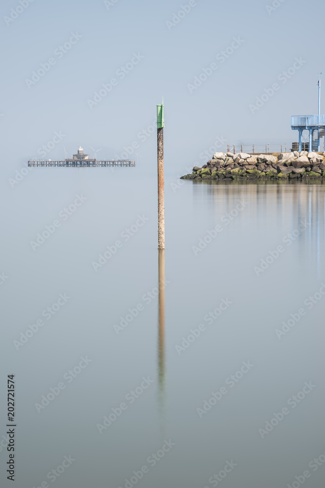 Minimalist fine art landscape  image of lifeguard tower in juxtaposition with old derelict pier in background