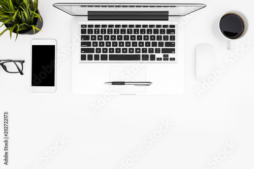Photos Clean white office desk table with laptop, cup of coffee and supplies