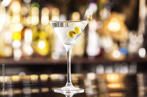 Closeup glass of martini dry cocktail with olives at bar counter background. photo