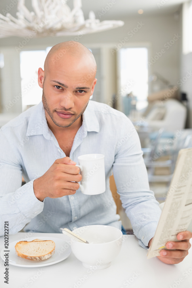 Man drinking coffee while reading newspaper at home Man drinking coffee while reading newspaper at home