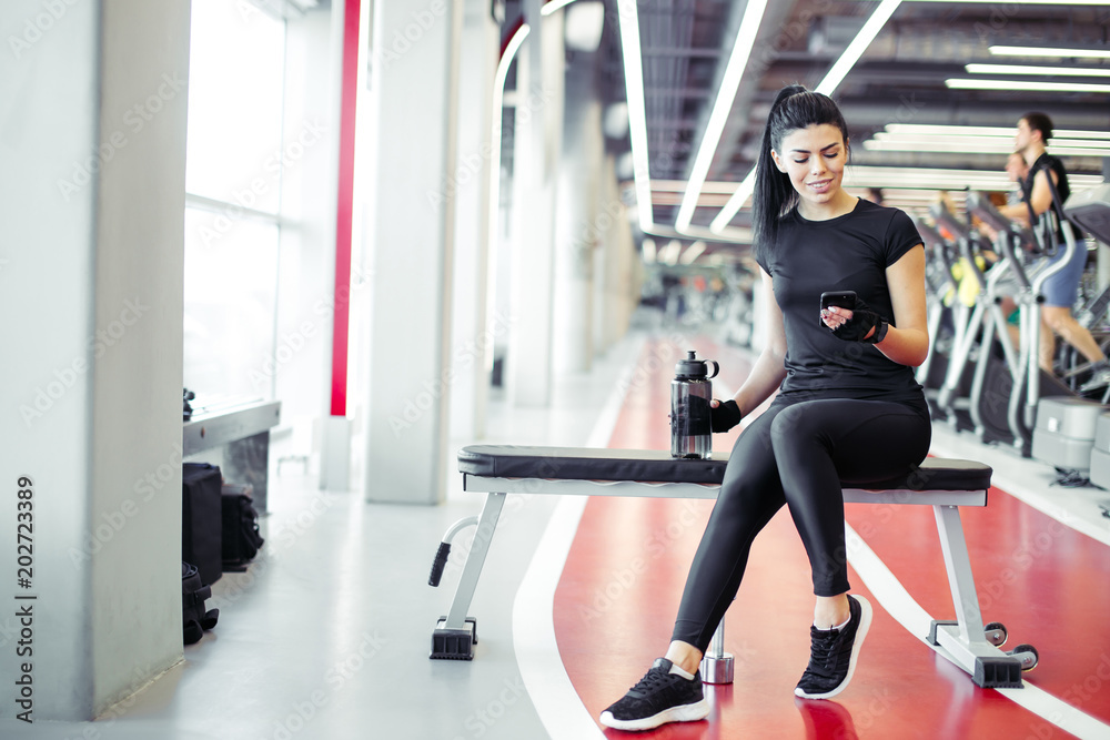 Φωτογραφία sporty girl after training looks at their results and counts calories on smartph