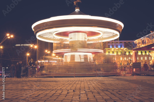 Brightly illuminated traditional carousel at night city street festival