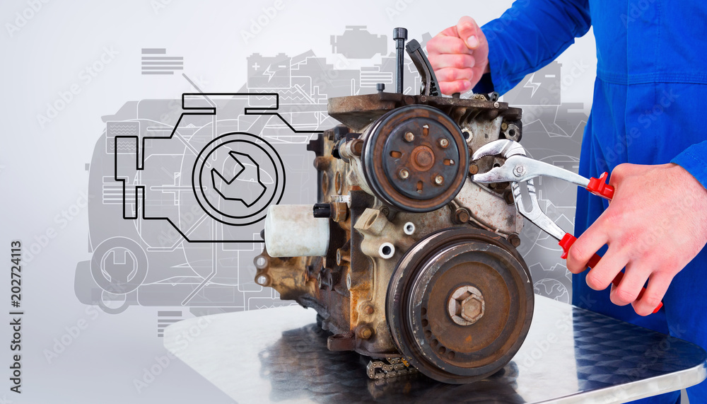 Male mechanic repairing car engine against grey vignette Male mechanic repairing car engine against grey vignette