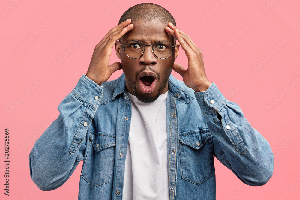Φωτογραφία Portrait of stunned embarrassed male has healthy dark skin looks in dissatisfact