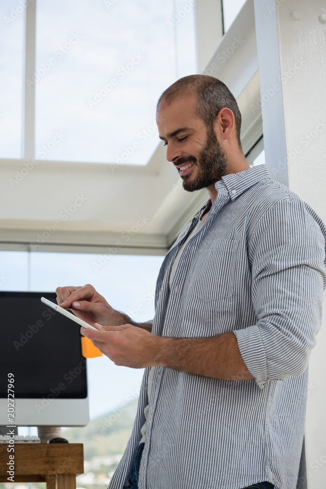 Low angle view of designer using digital tablet while leaning on wall