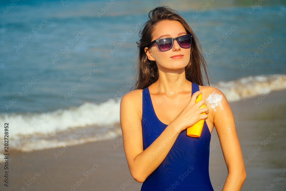 beautiful woman rubs sunscreen on his shoulder on the beach beautiful woman rubs sunscreen on his shoulder on the beach