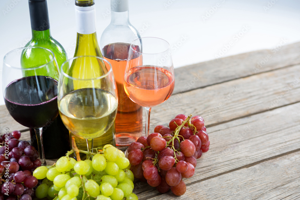 Bunches of various grapes with wine glass and bottles