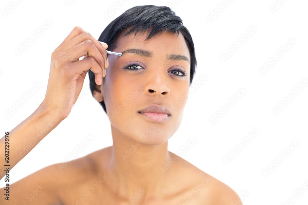 Beautiful black haired woman plucking her eyebrows Beautiful black haired woman plucking her eyebrows