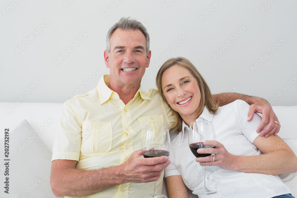 Happy couple with wine glasses sitting on sofa Happy couple with wine glasses sitting on sofa