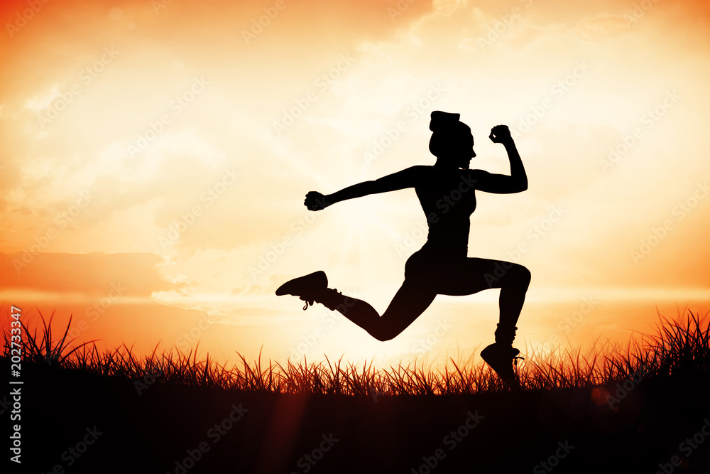 Fit brunette running and jumping against orange sunrise