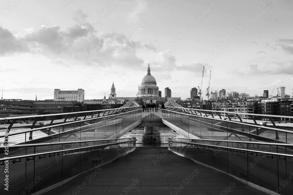 Millennium bridge with Saint Paul Cathedral in the evening in London, UK. Bridge over river Thames. Black and white