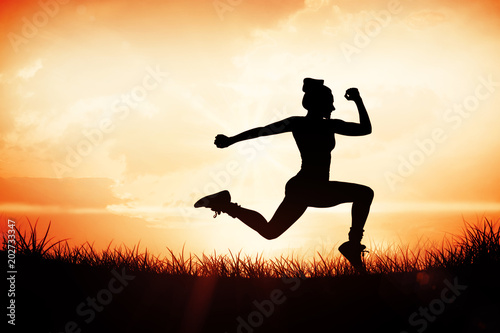 Fit brunette running and jumping against orange sunrise