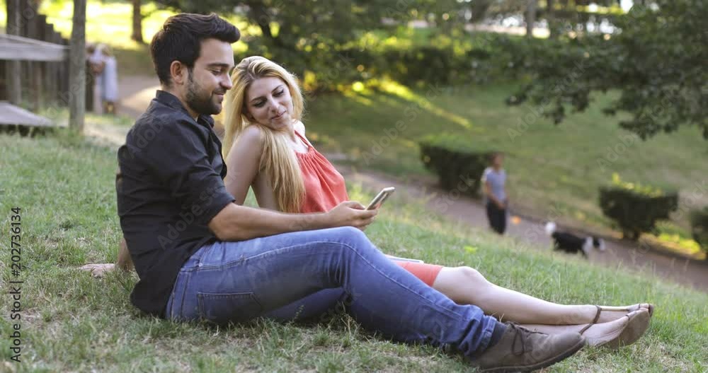 young couple on the lawn relaxes using the smartphone young couple on the lawn relaxes using the smartphone