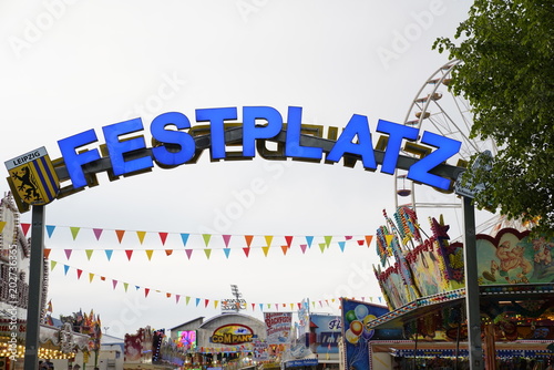 Amusement park (Festplatz) sign at the entrance with carousels in the background in Leipzig, Germany (Kleinmesse) photo