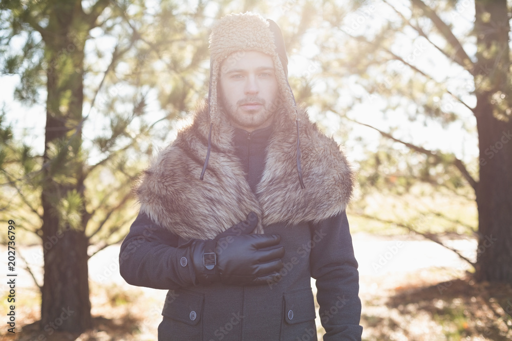 Handsome young man in warm clothing standing in forest Handsome young man in warm clothing standing in forest