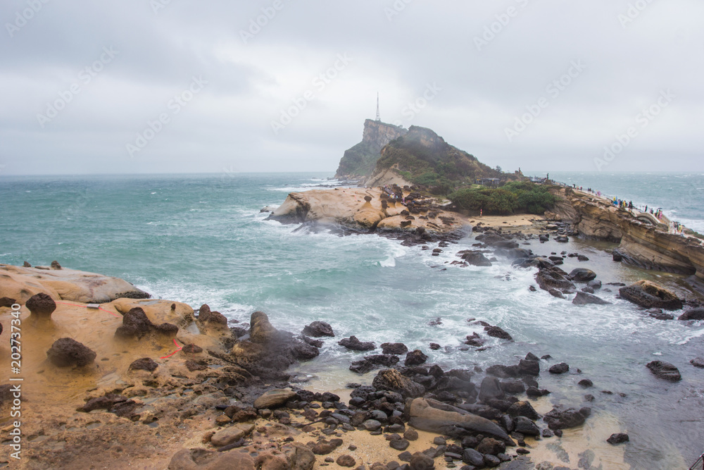 YEHLIU, TAIWAN - OCT11, 2016: Tourists at the Yeliu (Yehliu) Geopark in Wanli District, New Taipei, Taiwan at a rainy, windy and overcast day.