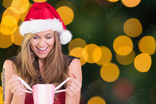 Festive blonde opening a gift bag against blurry yellow christmas light circles