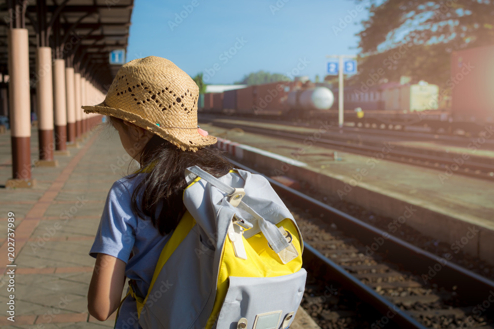 Young girl waiting for a train at railway station.