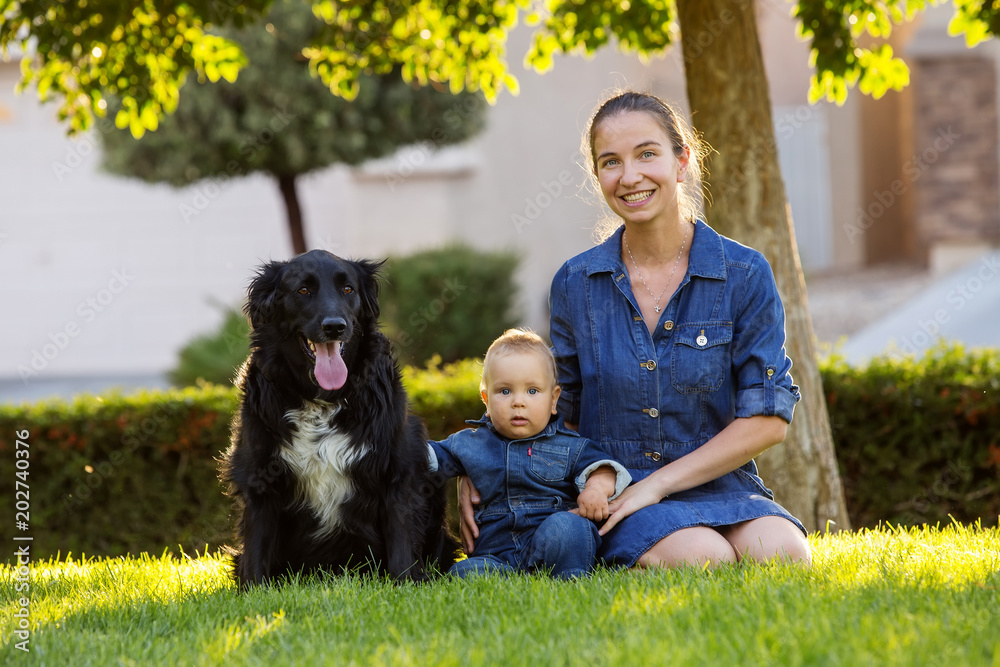 A mother with baby son and black dog in green neighborhood A mother with baby son and black dog in green neighborhood