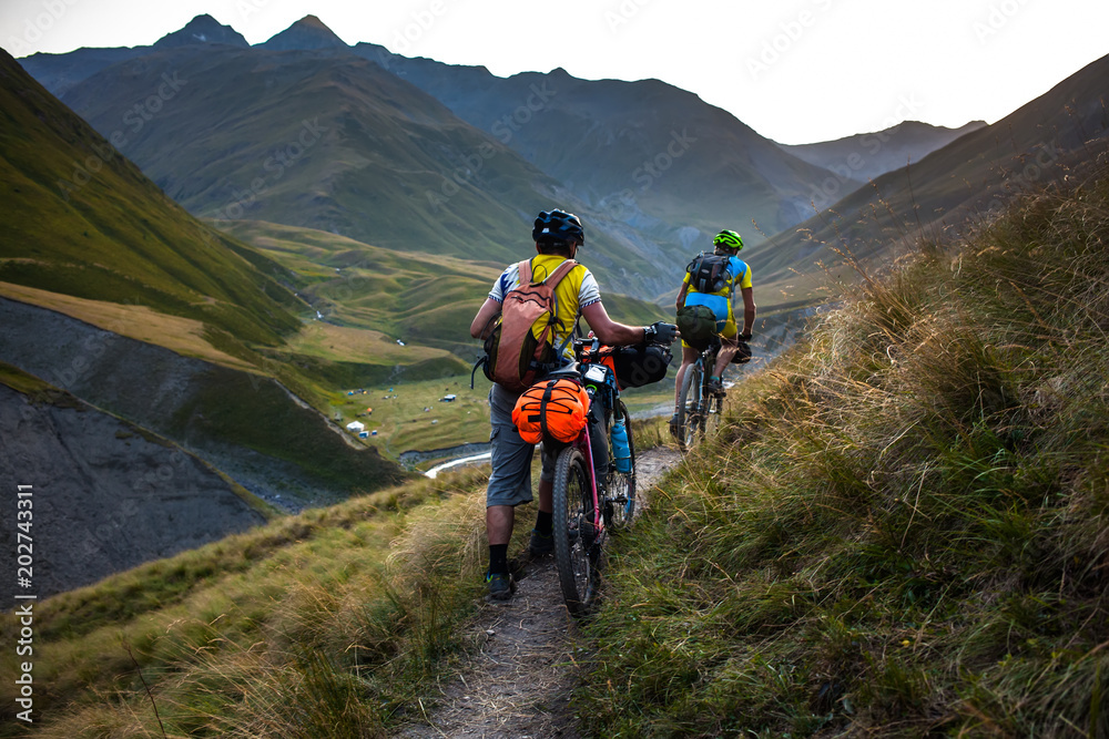 Biker pushes his bicycle up in high Caucasus mountains