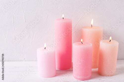 Pink  burning candles on white textured background.