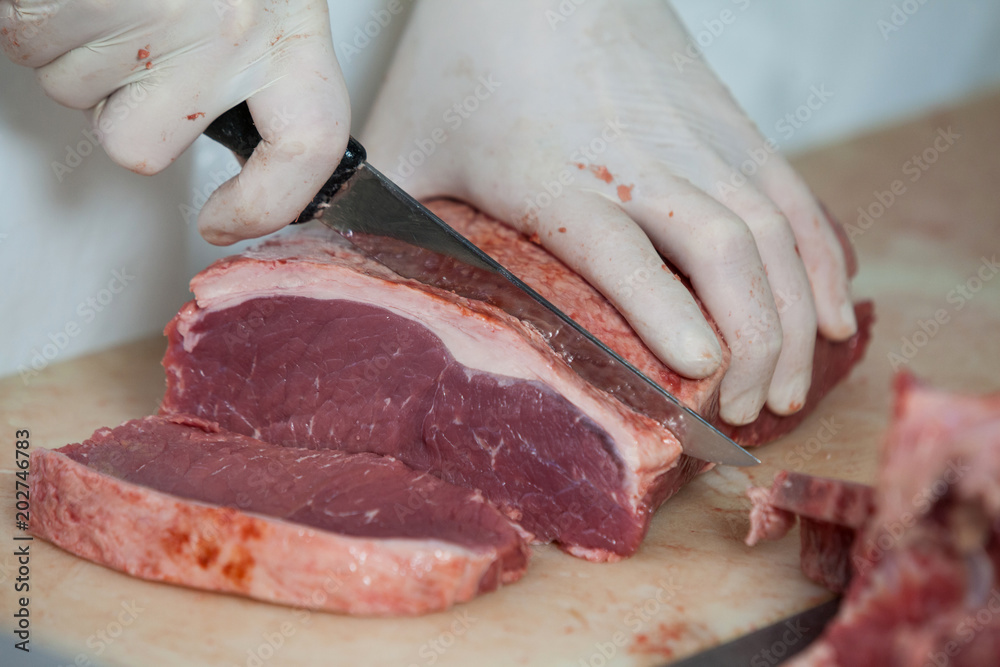Butcher cutting meat at meat factory