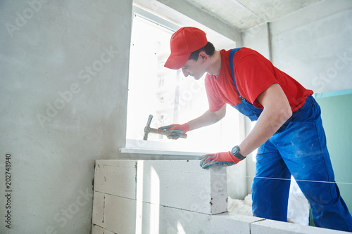 walling. bricklayer installing wall from autoclaved aerated concrete blocks