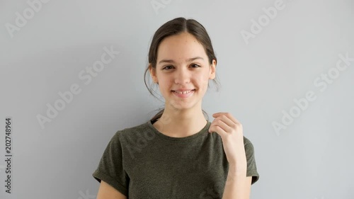 Slow motion of beautiful cute teenage girl smiling naturaly on gray background photo