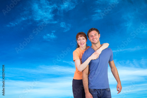 Happy couple looking at camera against blue sky