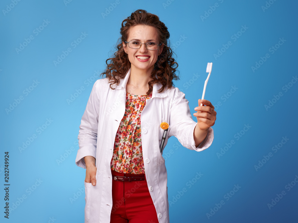 happy pediatrician doctor showing toothbrush on blue