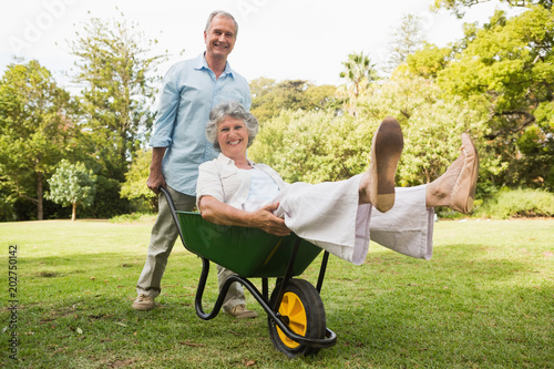 Cheerful man pushing his wife in a wheelbarrow