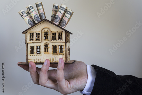Real estate and mortgage investment. Being an easy way homeowner.Dollars and wooden house on the white background.