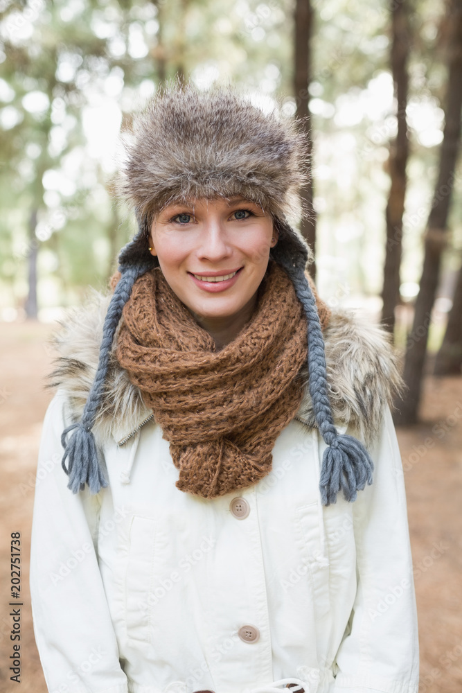 Woman wearing fur hat with woolen scarf and jacket in woods Woman wearing fur hat with woolen scarf and jacket in woods