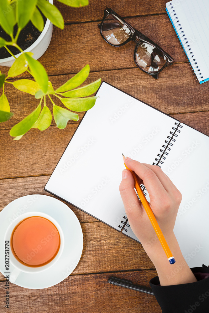 Εκτύπωση καμβά Businesswomans hand writing with pencil against close up view of business stuff